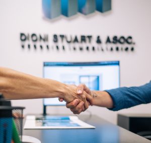 cliente y vendedor cerrando trato mientras se estrechan la mano en las oficinas de Dioni Stuart